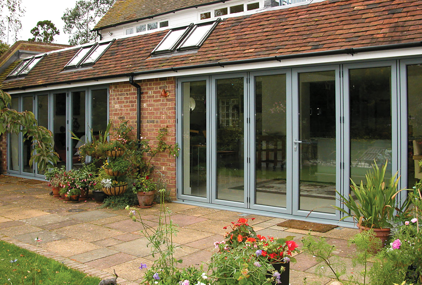 Contemporary styled modern aluminium sliding doors opening onto a beautiful garden with a swimming pool